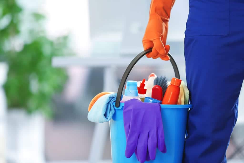 Cleaning person holding bucket of supplies.