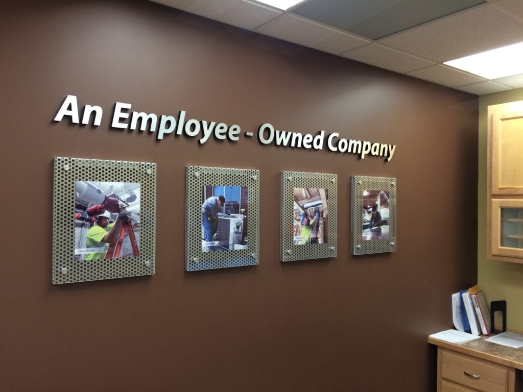 A brown wall with the words An Employee-Owned Company above four photos. 