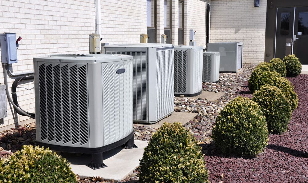 A row of commercial air conditioners outside a brick buildling