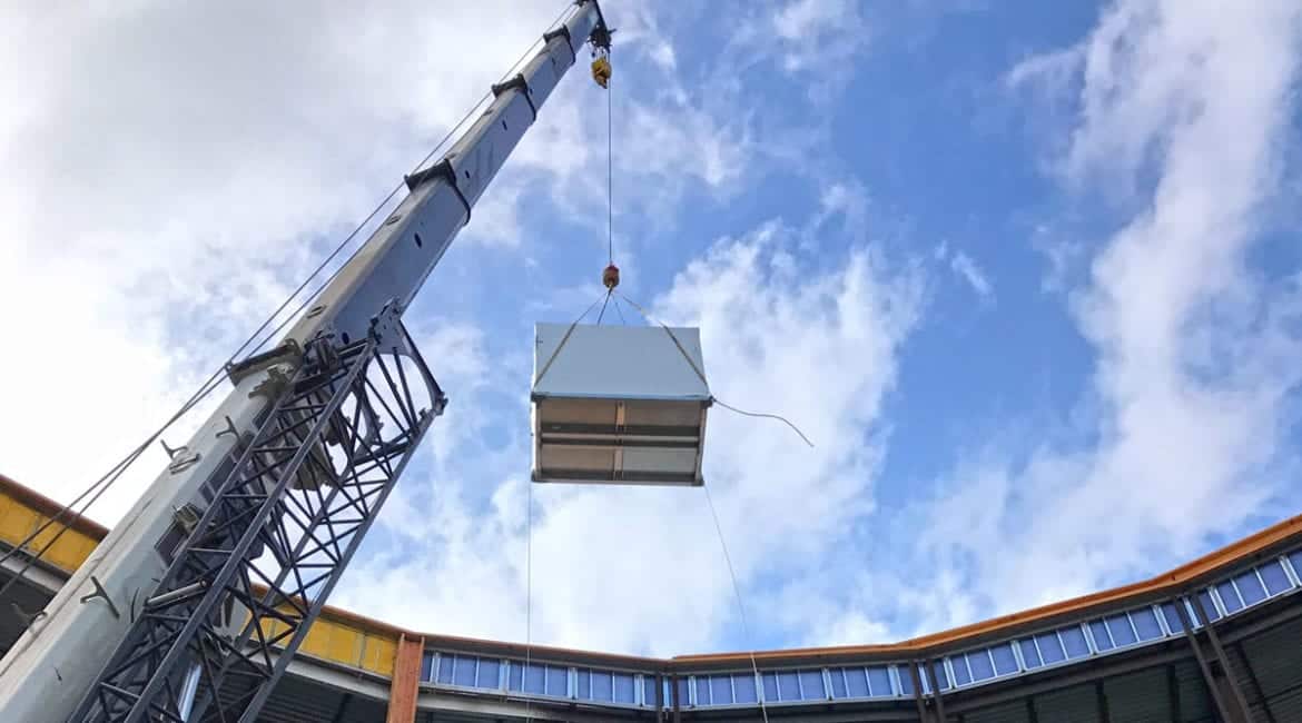 A crane lifting a commercial air conditioner to the roof of the Mountrail-Williams Electric Cooperative building in Williston, ND