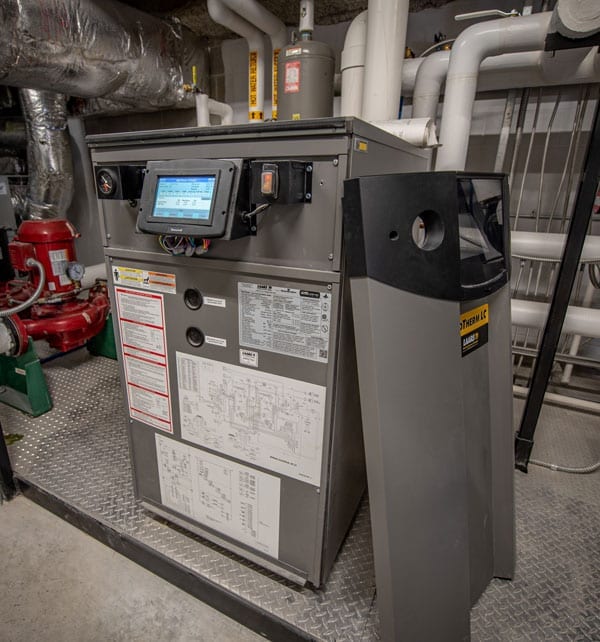 A gray LAARS commercial boiler in a boiler room of an apartment building