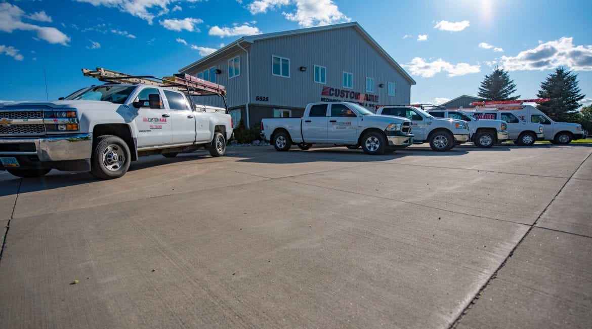 A fleet of white Custom Aire trucks lined up outside the company’s office in Grand Forks, ND.