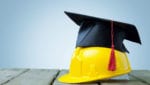 Graduation cap on top of yellow hard hat.