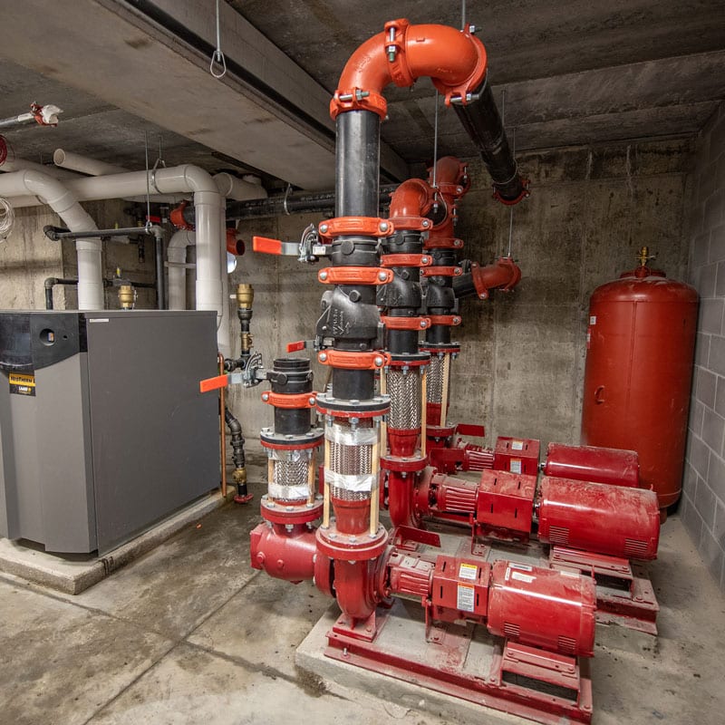 A large network of red pipes in the mechanical room of an apartment building