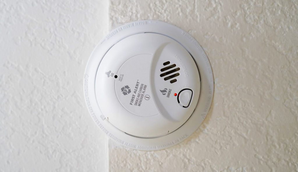 A white carbon monoxide detector on a white wall