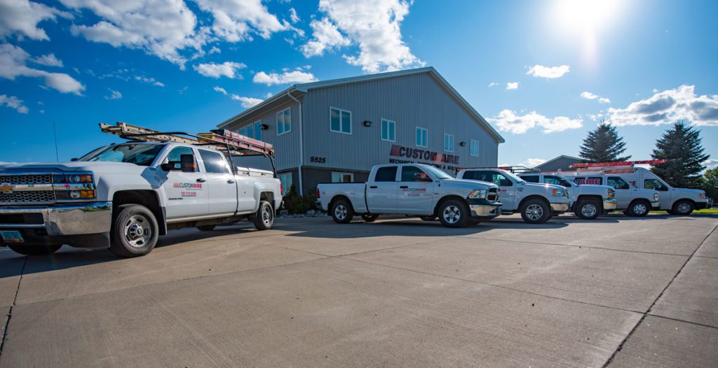 Some of Custom Aire’s fleet vehicles arranged neatly in front of Custom Aire headquarters